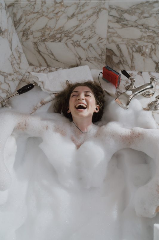 young lady listening to music in bubble bath