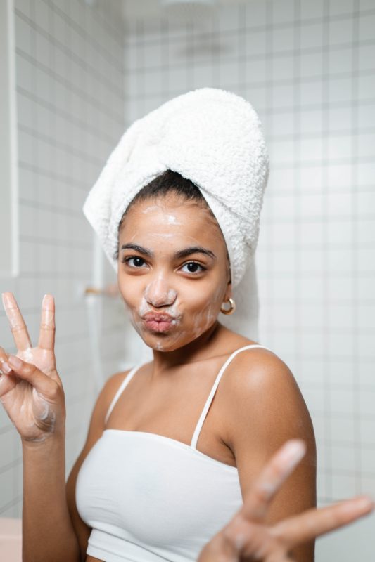 woman with face cleanser holding up peace signs