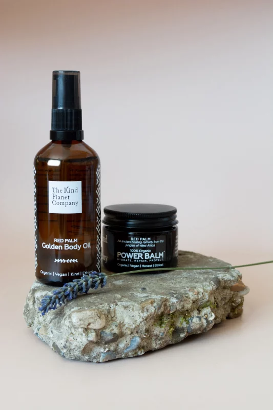 golden body oil and power balm sat on top of a rock with a lavender stem